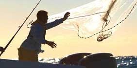 Pescador tirando la red de pesca en el mar